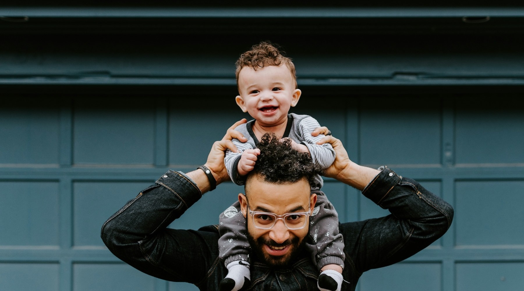 a child sitting on a parents shoulders