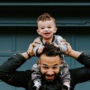 a child sitting on a parents shoulders